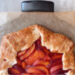 A peachy keen galette on parchment paper waiting to be served.