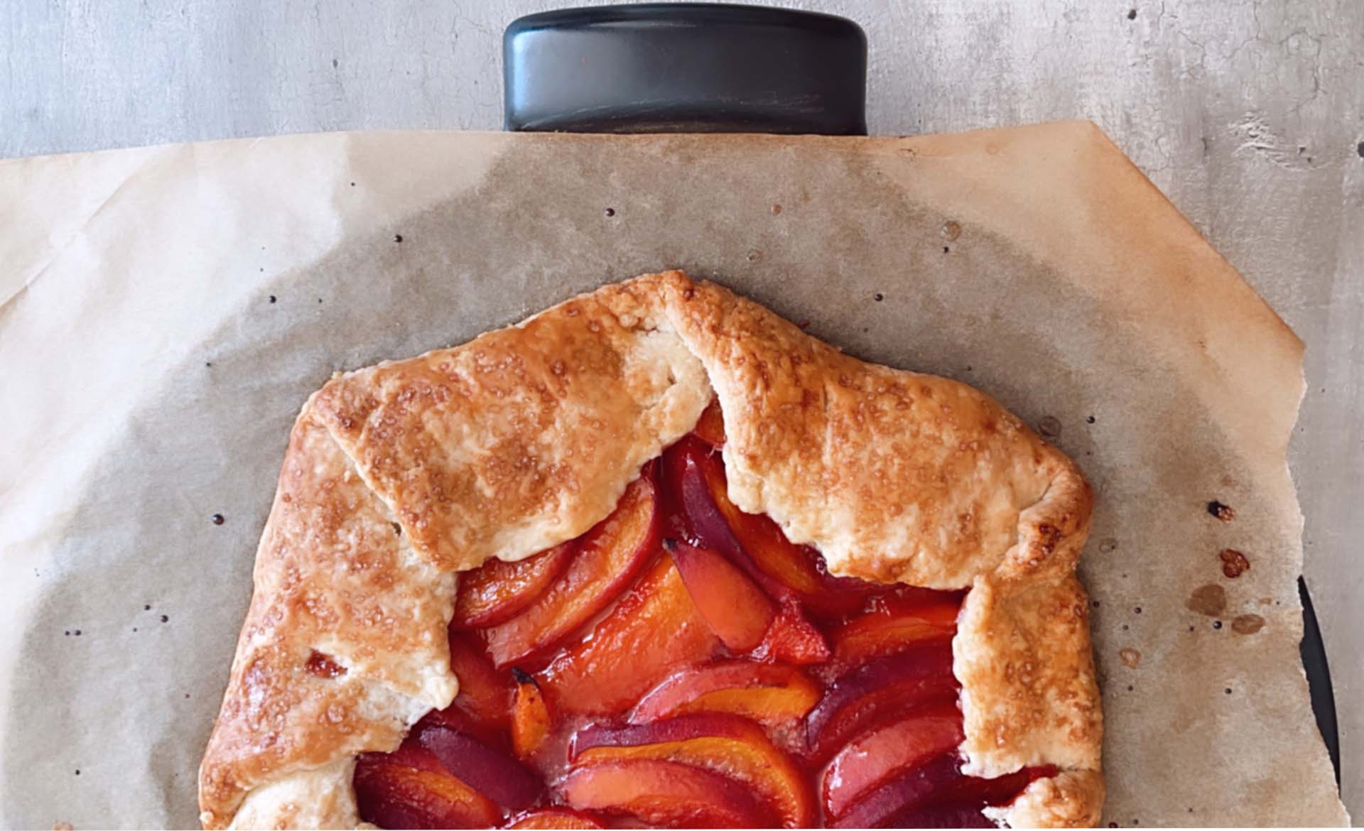 A peachy keen galette on parchment paper waiting to be served.