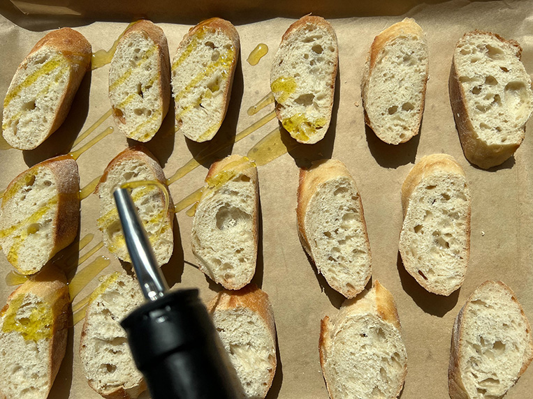 Drizzling olive oil on small pieces of bread.