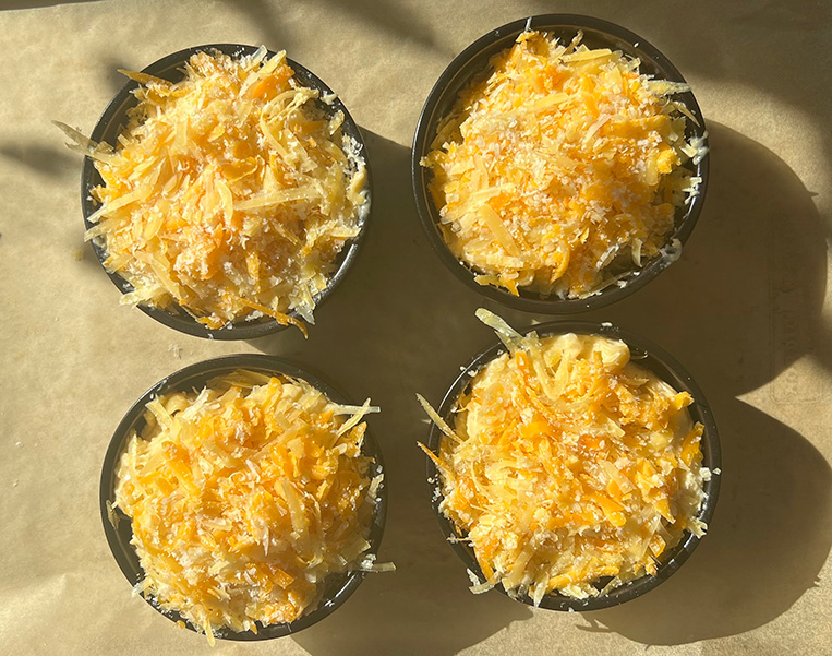 Ramekins filled with Mac and Cheese, topped with grated cheese.