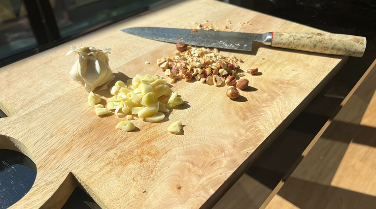 Chopped garlic and hazelnuts on a cutting board.